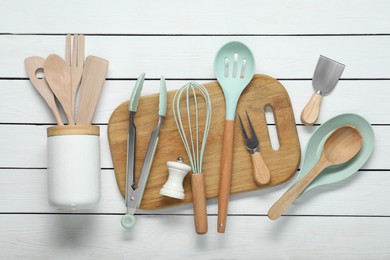 Set of different kitchen utensils on white wooden table, flat lay