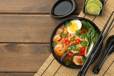 Photo of Delicious ramen with shrimps and egg in bowl served on wooden table, flat lay with space for text. Noodle soup