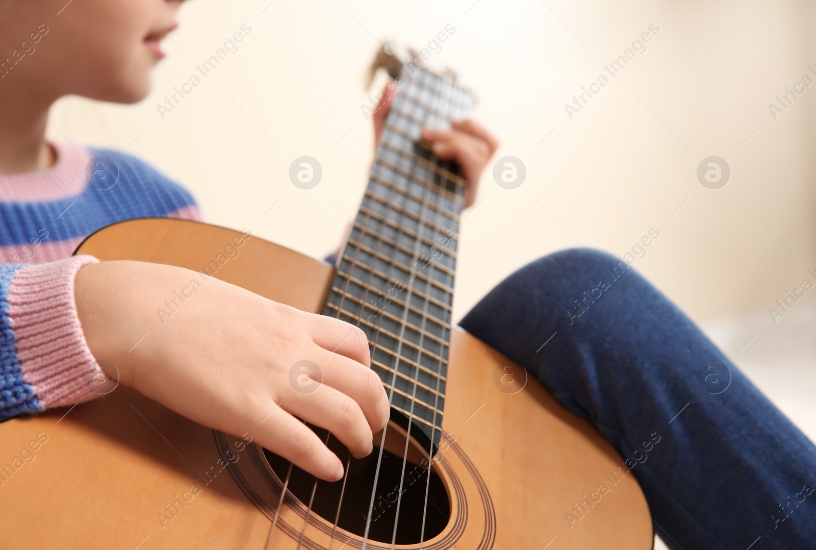 Photo of Little girl playing wooden guitar, closeup view