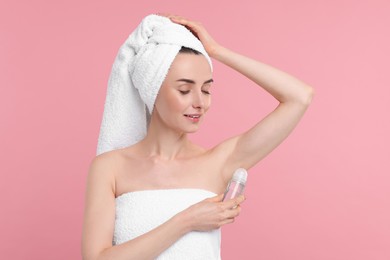 Beautiful woman applying deodorant on pink background