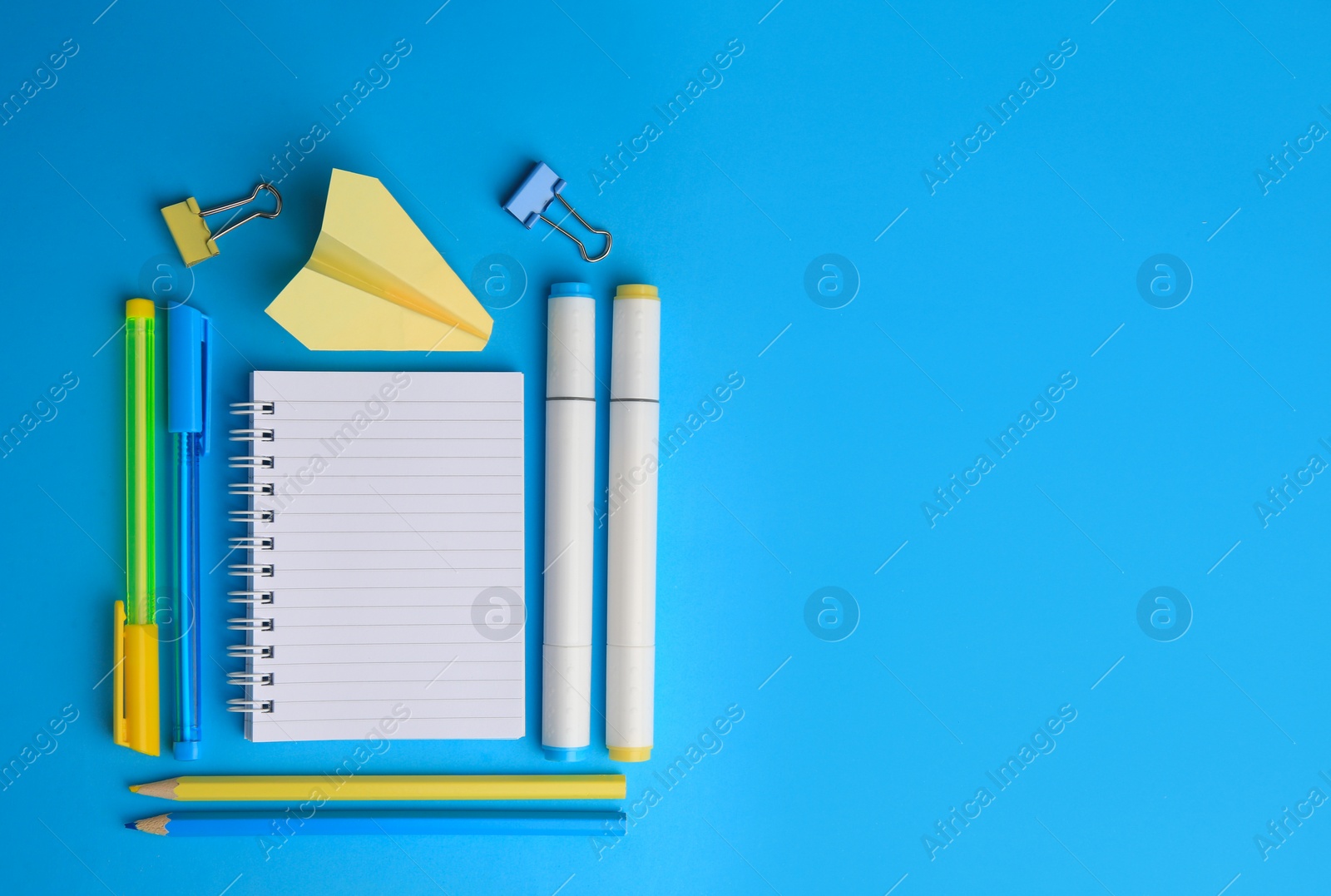 Photo of Paper plane and different school stationery on light blue background, flat lay with space for text. Back to school