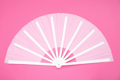 Stylish white hand fan on pink background, top view