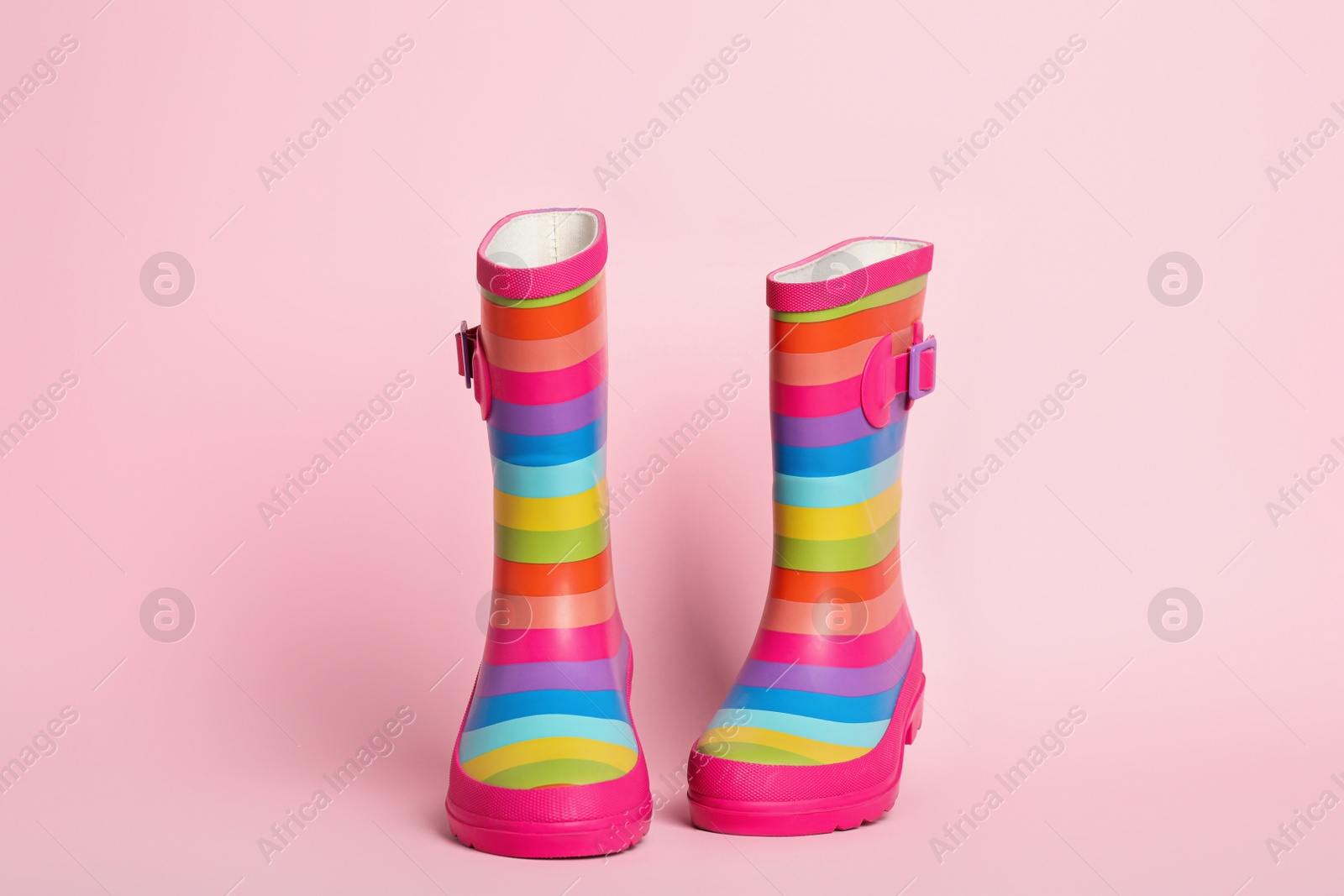 Photo of Pair of striped rubber boots on pink background