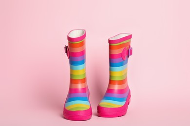 Photo of Pair of striped rubber boots on pink background