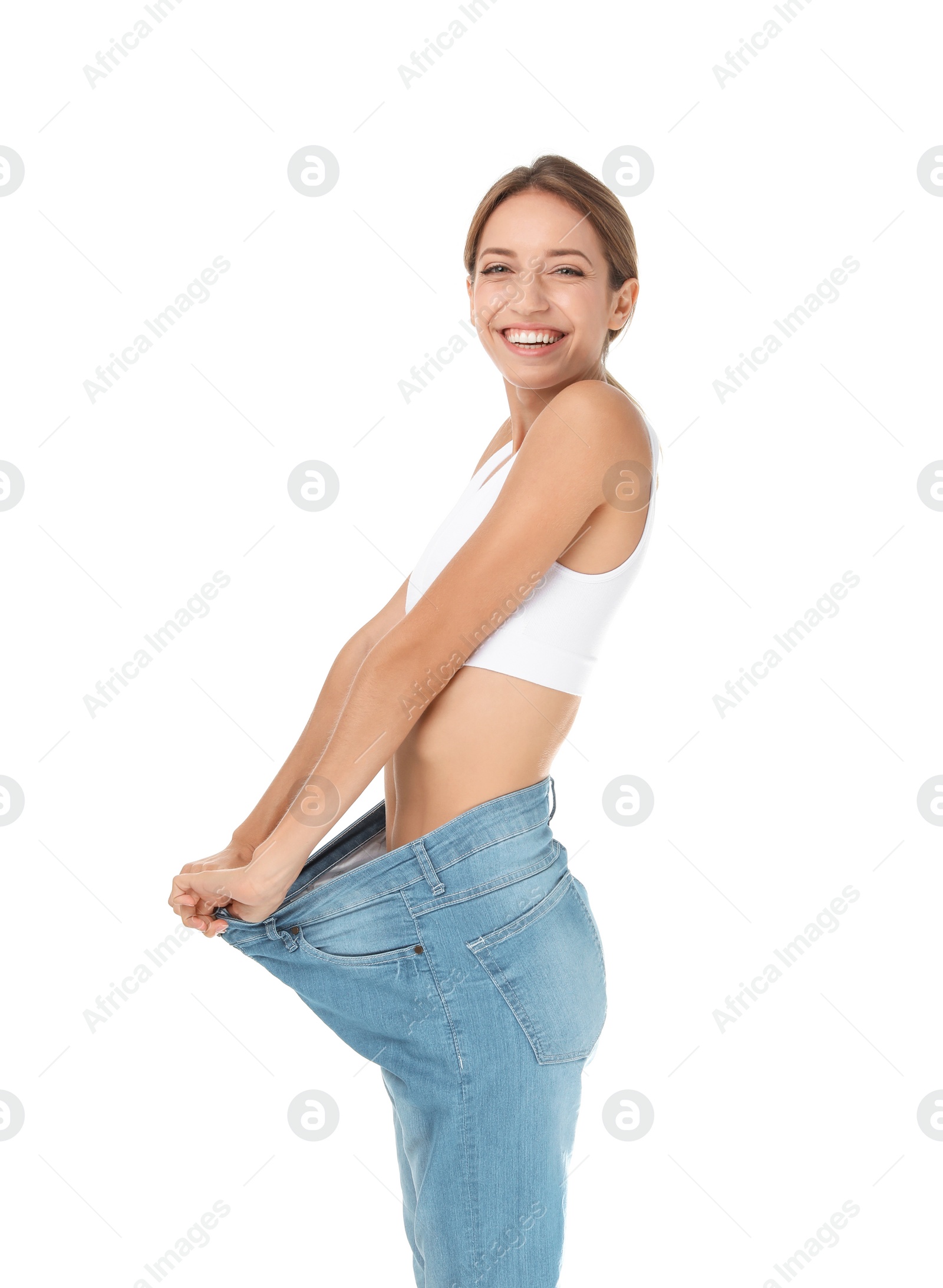 Photo of Young slim woman in old big jeans showing her diet results on white background