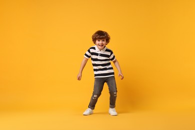 Happy little boy dancing on yellow background