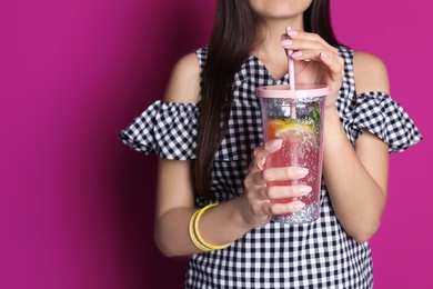 Photo of Young woman with tasty lemonade on color background. Natural detox drink