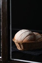 Fresh homemade bread in wicker basket, view through window