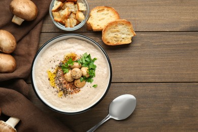 Photo of Delicious cream soup with mushrooms and ingredients on wooden table, flat lay. Space for text