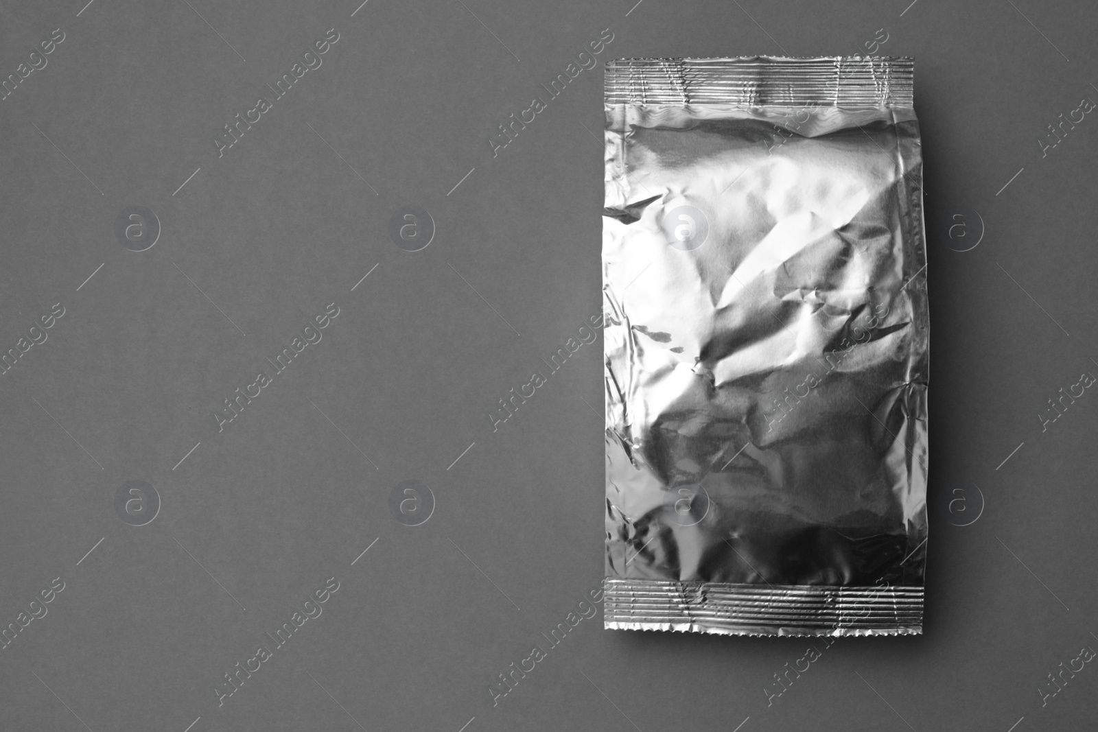 Photo of Blank foil package on grey background, top view. Space for text