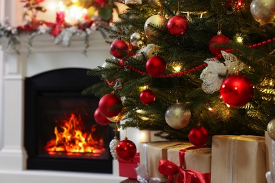 Beautiful Christmas tree and gifts near fireplace indoors