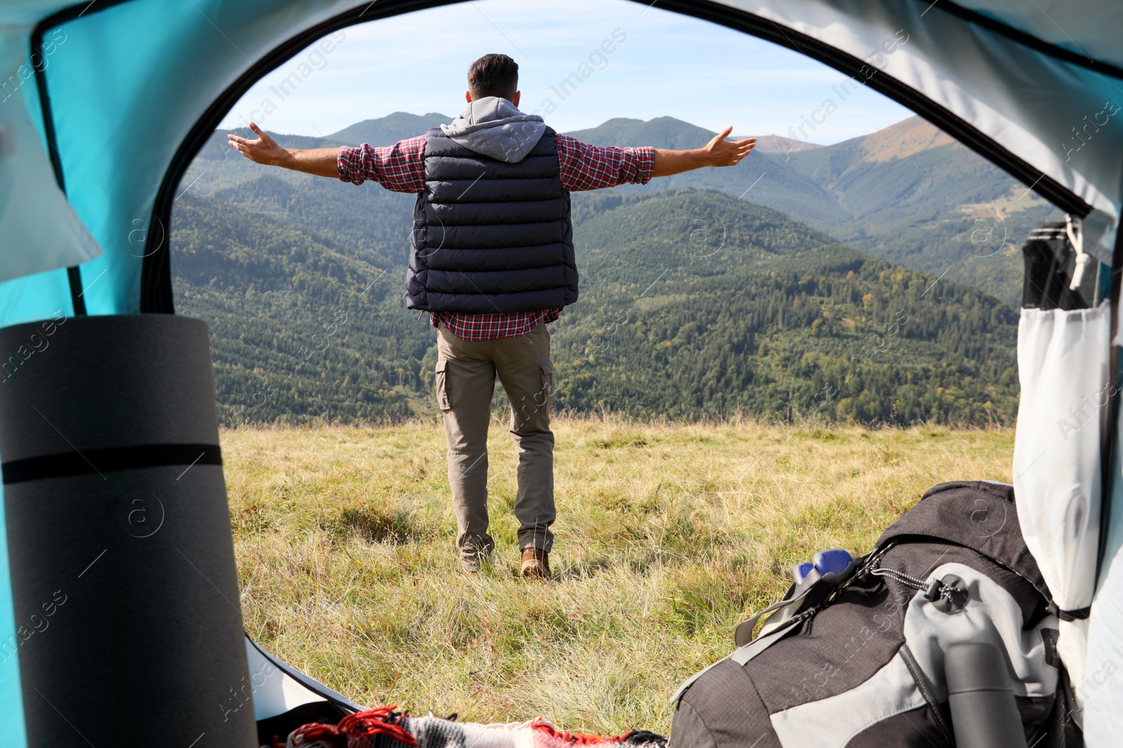 Photo of Man in mountains on sunny day, view from camping tent