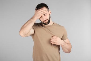 Photo of Young man suffering from headache on light background