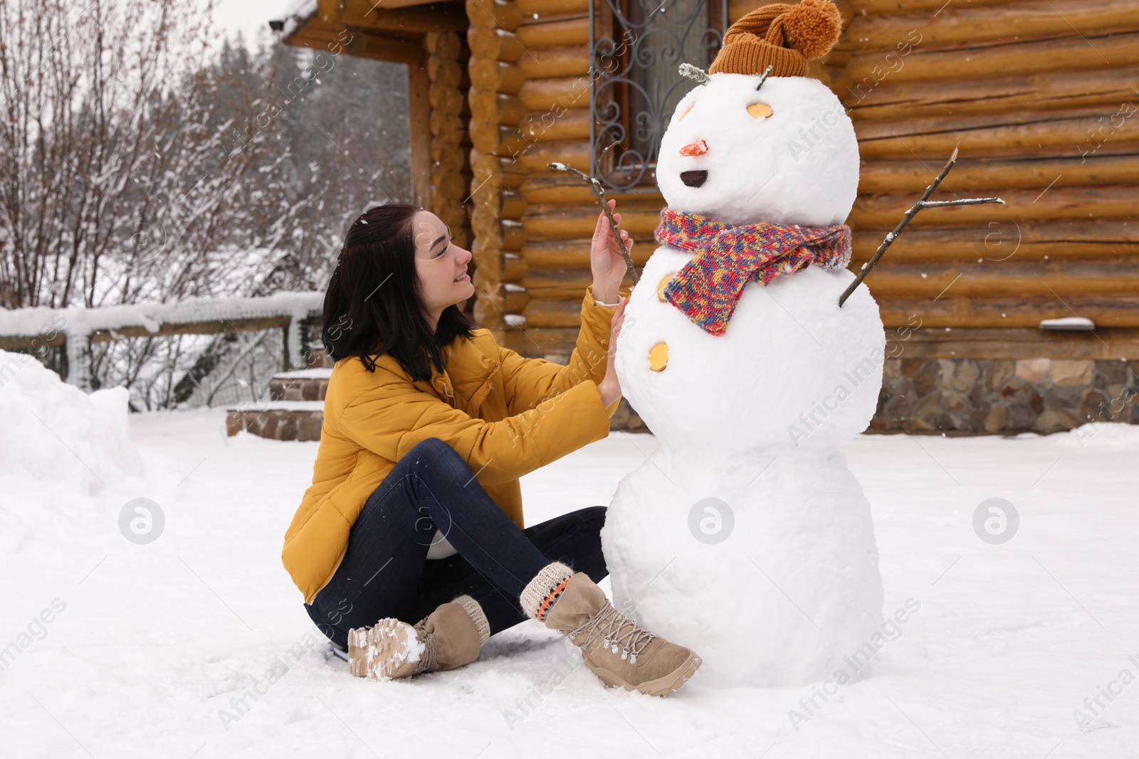 Photo of Young woman near funny snowman outdoors. Winter vacation