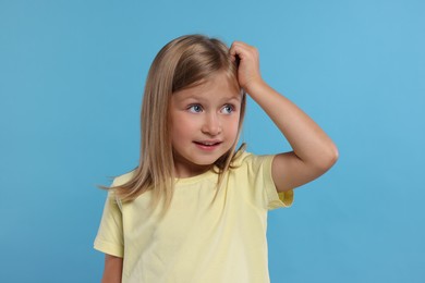 Photo of Portrait of embarrassed little girl on light blue background
