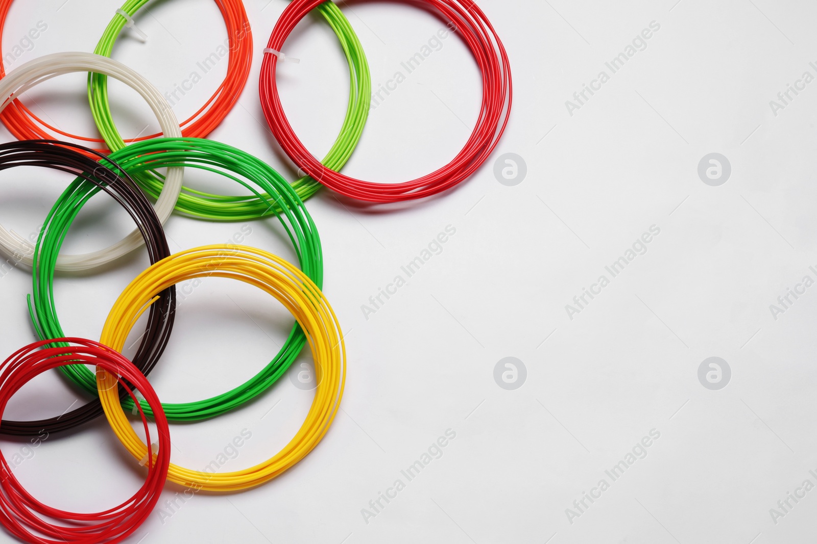 Photo of Colorful plastic filaments for 3D pen on white background, flat lay. Space for text