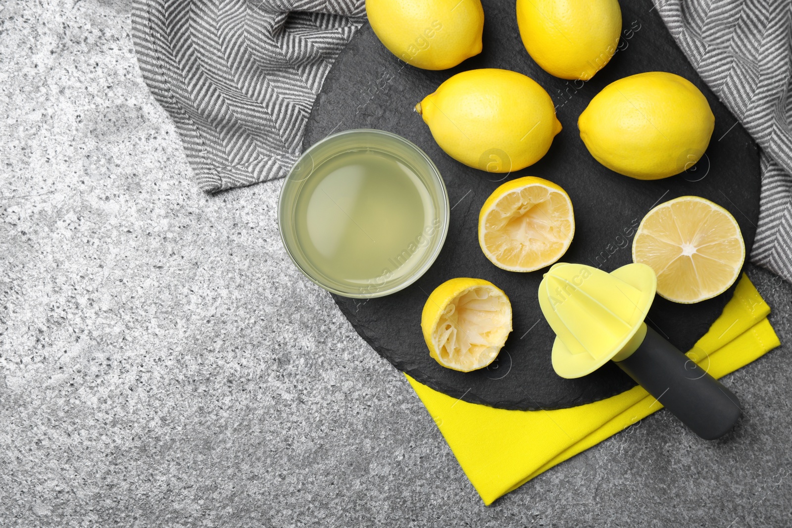 Photo of Flat lay composition with freshly squeezed lemon juice and reamer on grey table