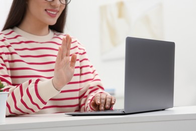 Photo of Woman having video chat via laptop at white table indoors, closeup