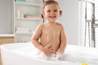 Photo of Cute little girl in foamy bath at home