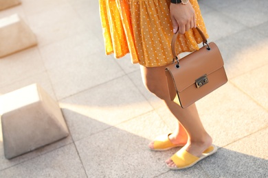 Young woman with stylish brown bag on city street, closeup