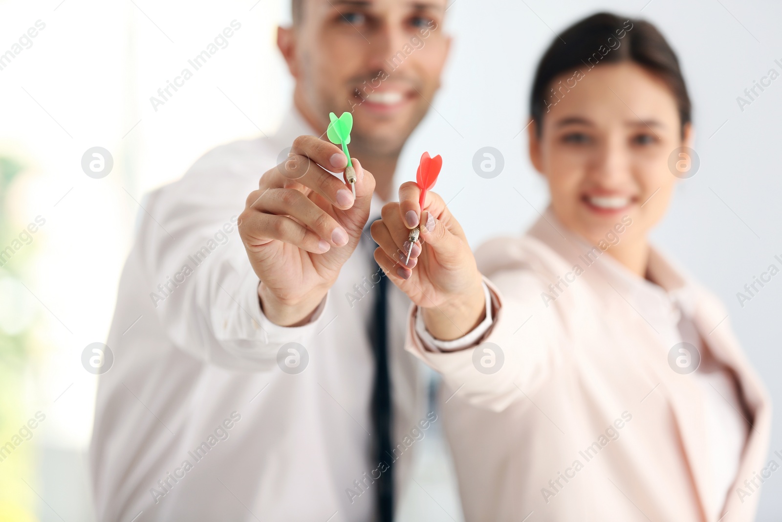 Photo of Happy employees in office, focus on hands with darts