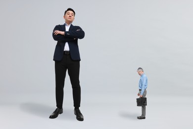 Image of Giant boss and sad small man on light background