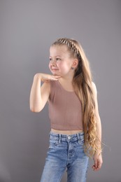 Little girl with braided hair on grey background