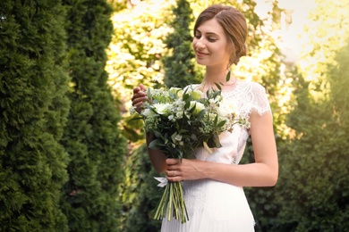 Gorgeous bride in beautiful wedding dress with bouquet outdoors