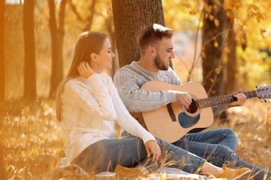 Photo of Young couple with guitar in autumn park