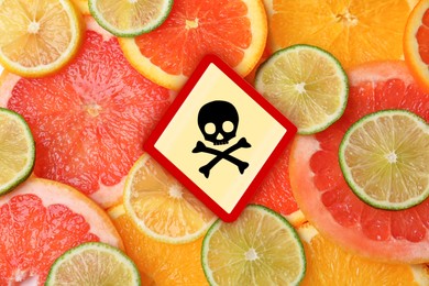 Image of Skull and crossbones sign on different fresh citrus fruits, top view. Be careful - toxic