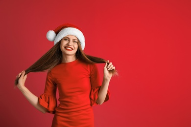 Young beautiful woman in Santa hat on color background. Christmas celebration