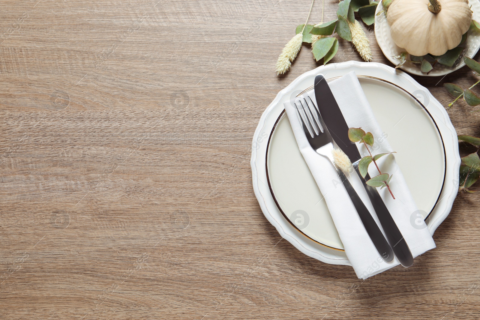 Photo of Festive table setting with floral decor and pumpkins  on wooden background, flat lay. Space for text