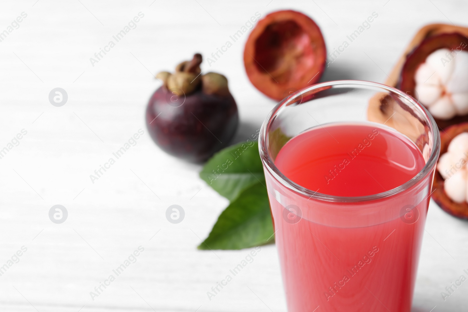 Photo of Delicious fresh mangosteen juice in glass on white table, closeup. Space for text