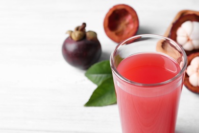 Photo of Delicious fresh mangosteen juice in glass on white table, closeup. Space for text