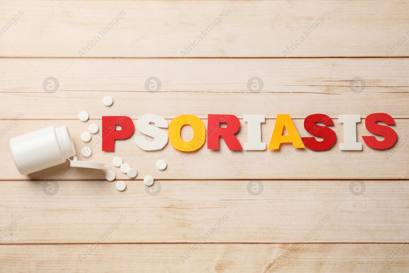 Photo of Word Psoriasis made of paper letters and pills on wooden table, flat lay