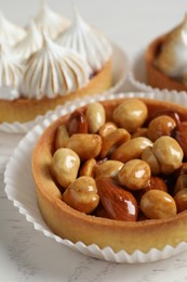Different tartlets on white wooden table, closeup. Tasty dessert