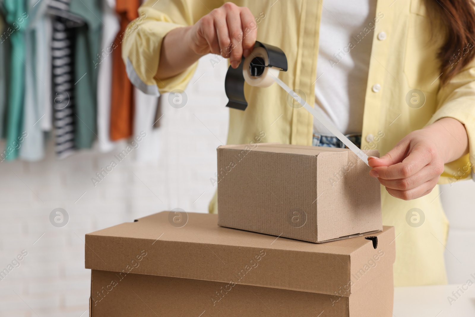 Photo of Seller packing cardboard box in office, closeup