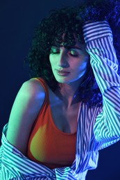 Beautiful young woman posing on color background in neon lights