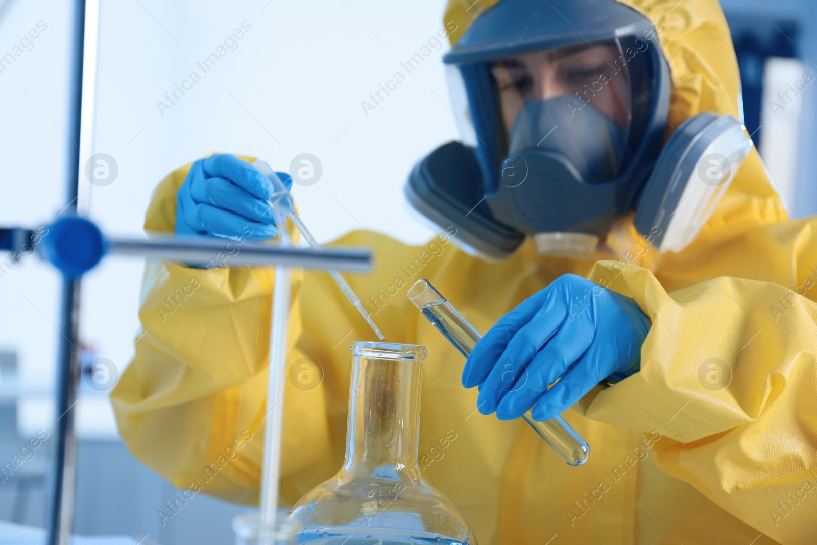 Photo of Scientist in chemical protective suit working at laboratory, focus on hands. Virus research