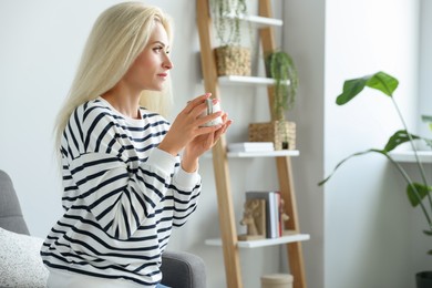 Beautiful woman with cup of drink in stylish room