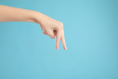 Photo of Woman imitating walk with hand on light blue background, closeup. Finger gesture