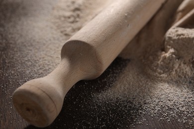 Rolling pin and scattered flour on wooden table, closeup