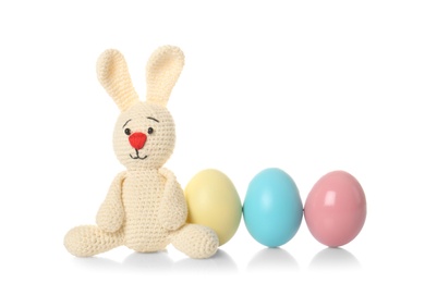 Cute Easter bunny toy and dyed eggs on white background