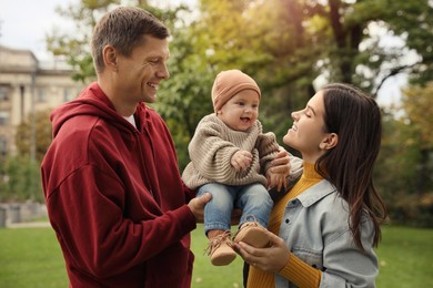 Happy parents with their adorable baby walking in park