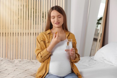 Photo of Beautiful pregnant woman taking pill at home