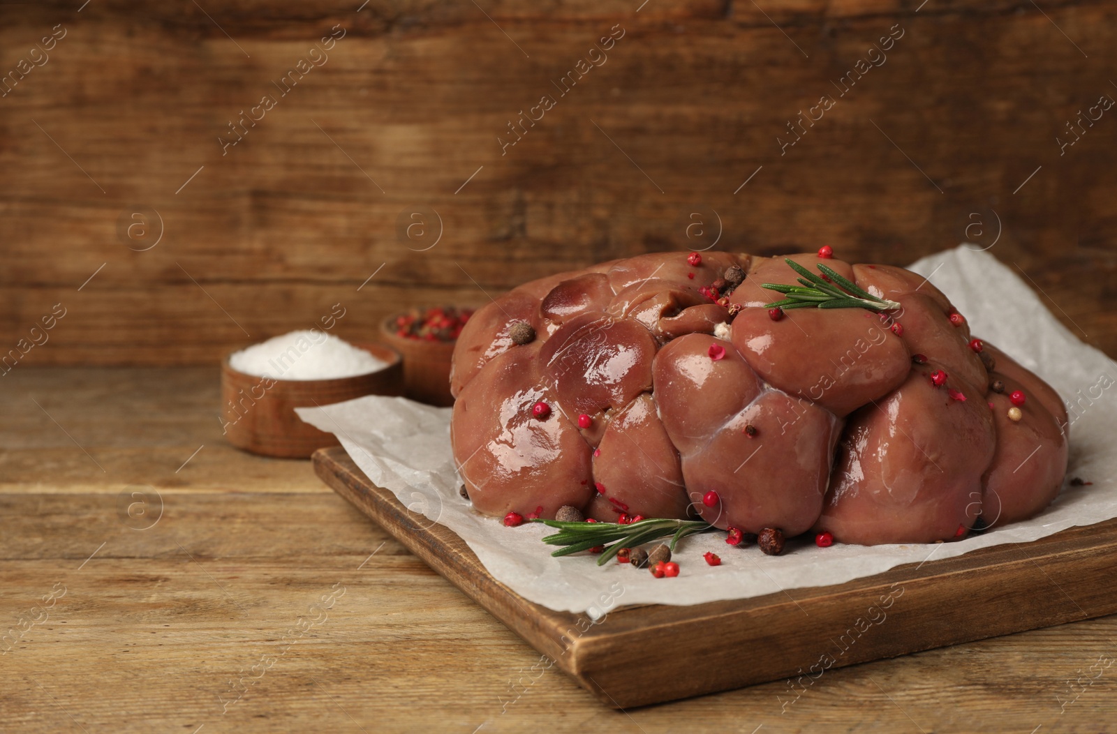 Photo of Fresh raw kidney meat with spices and rosemary on wooden table, space for text