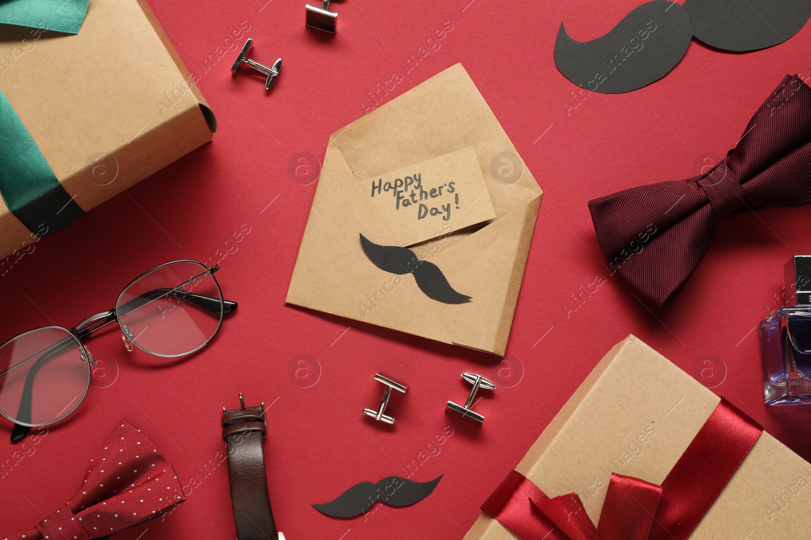 Photo of Card with phrase Happy Father's Day, gift boxes and men accessories on red background, flat lay