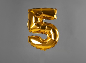 Golden number five balloon on grey background