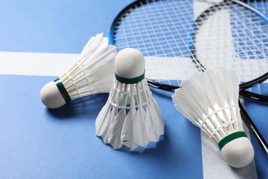 Photo of Feather badminton shuttlecocks and rackets on blue background, closeup