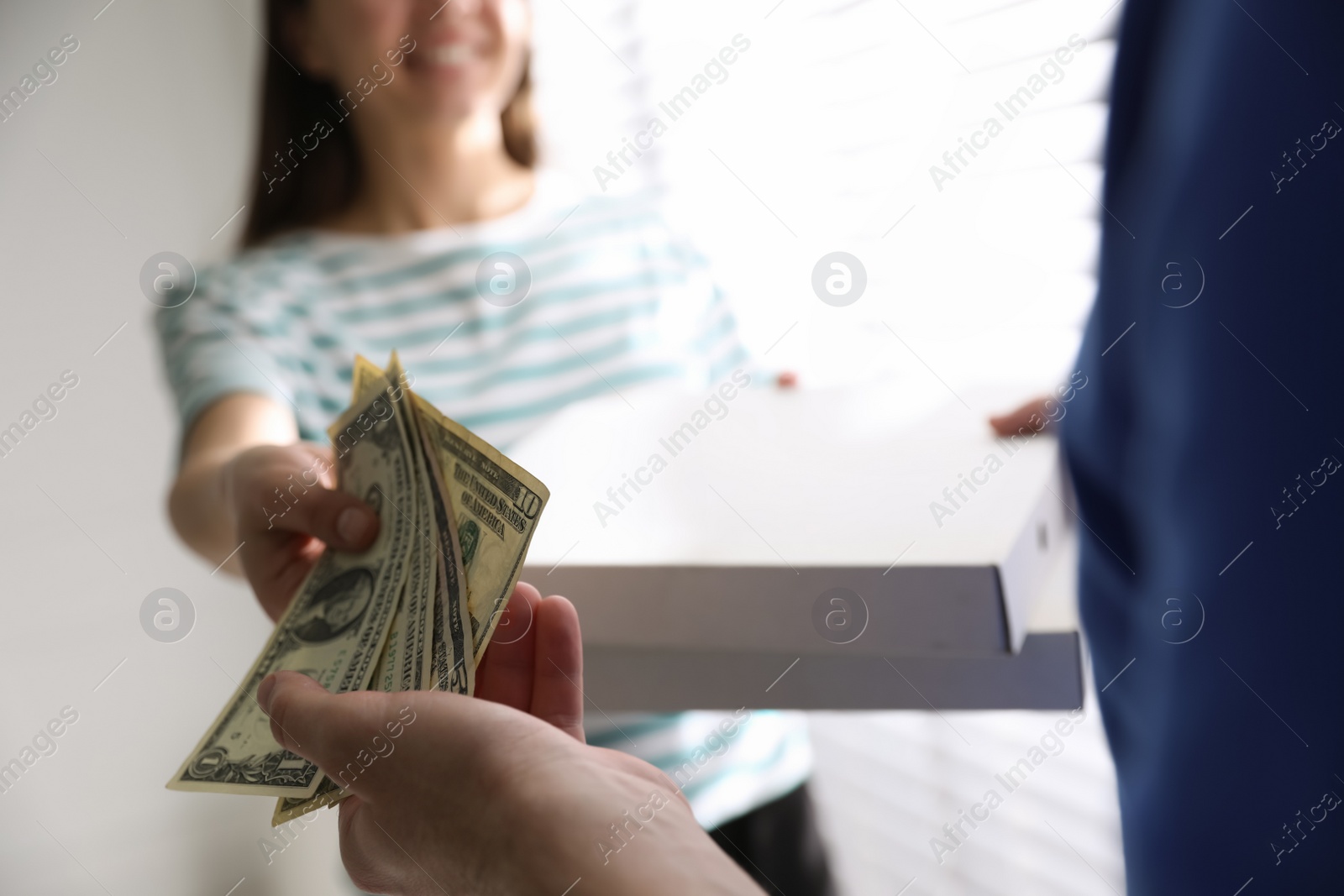 Photo of Woman giving tips to deliveryman indoors, closeup